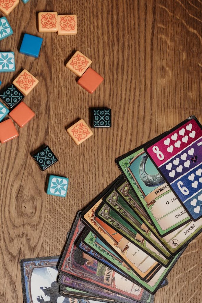 A variety of board game cards and tiles laid out on a wooden table, showcasing a fun and strategic gaming setup.