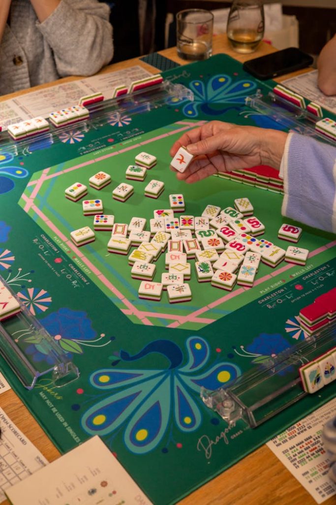 Playful evening of Mahjong with friends, featuring intricate tiles on a peacock green table.